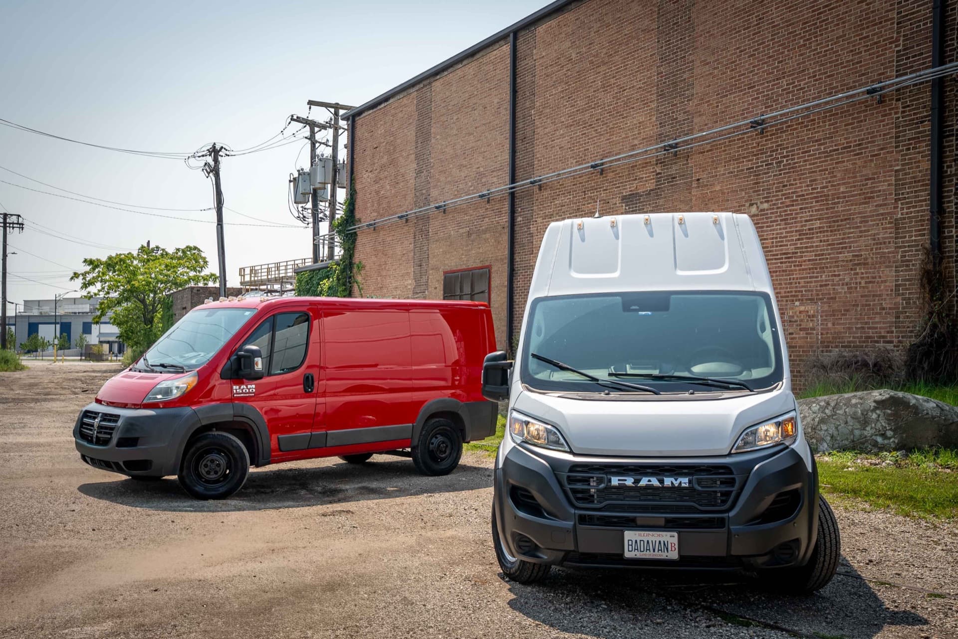 The red 1-ton and white 2-ton Ram Promaster vans parked outside a brick building