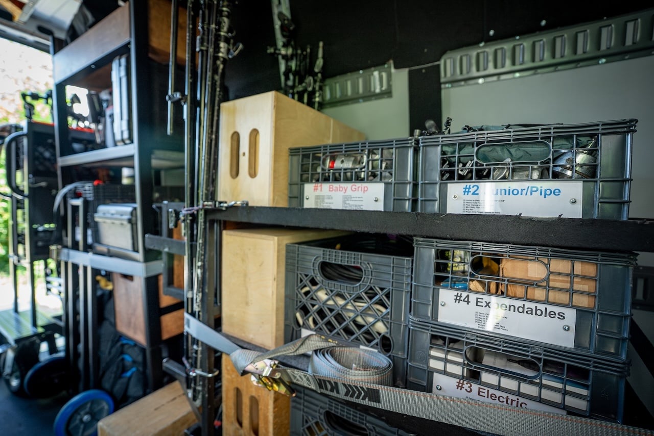 Organized shelving inside the 2 ton production truck holding camera cases, batteries and lighting equipment