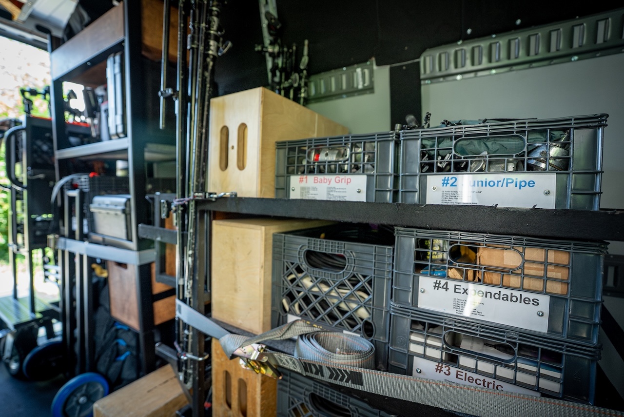 Organized shelving inside the 2 ton production truck holding camera cases, batteries and lighting equipment